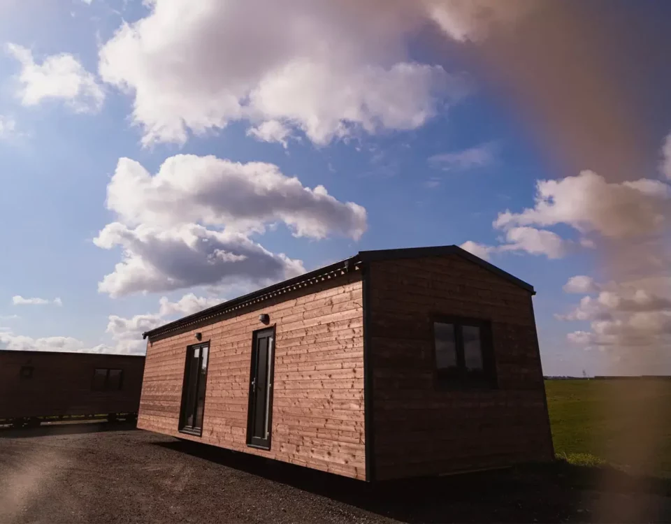 Dřevěný mobilní domek ABODES na pozemku.